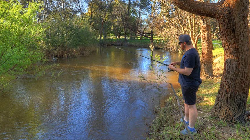 A man fishing on the banks of the Yea river