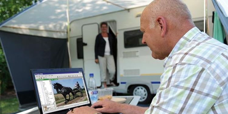 An older man using his laptop to take advantage of the free guest Wi-Fi at Yea Riverside Caravan Park