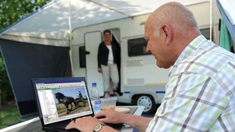 An older man using his laptop to take advantage of the free guest Wi-Fi at Yea Riverside Caravan Park