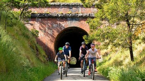 A family of four riding push bikes through an old rail tunnel